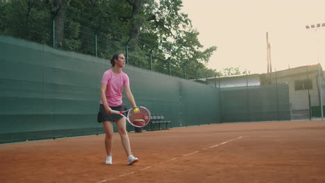 slow-motion-side-view-of-a-young-athlete-trains-the-serve-of-the-tennis-ball.-A-teenage-athlete-is-playing-tennis-on-a-court.-An-active-girl-is-powerfully-hitting-a-ball-during-sport-practicing
